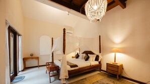 Une chambre à coucher avec un lit à baldaquin, une table de chevet, une commode, une lampe et un tapis décoratif.