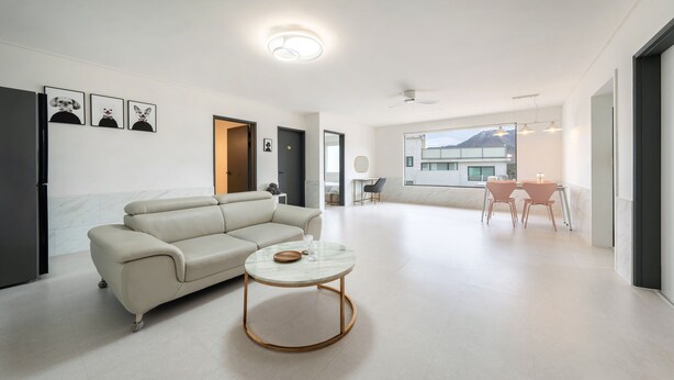 A modern living room with a sofa, a coffee table, and a dining area with chairs. There are framed pictures on the wall and a view of a building outside. - Gyeongju Purspet Dog Pension (Gyeongju)