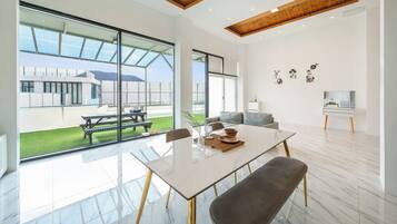 A modern interior with a glass dining table, a sofa, and a TV stand.