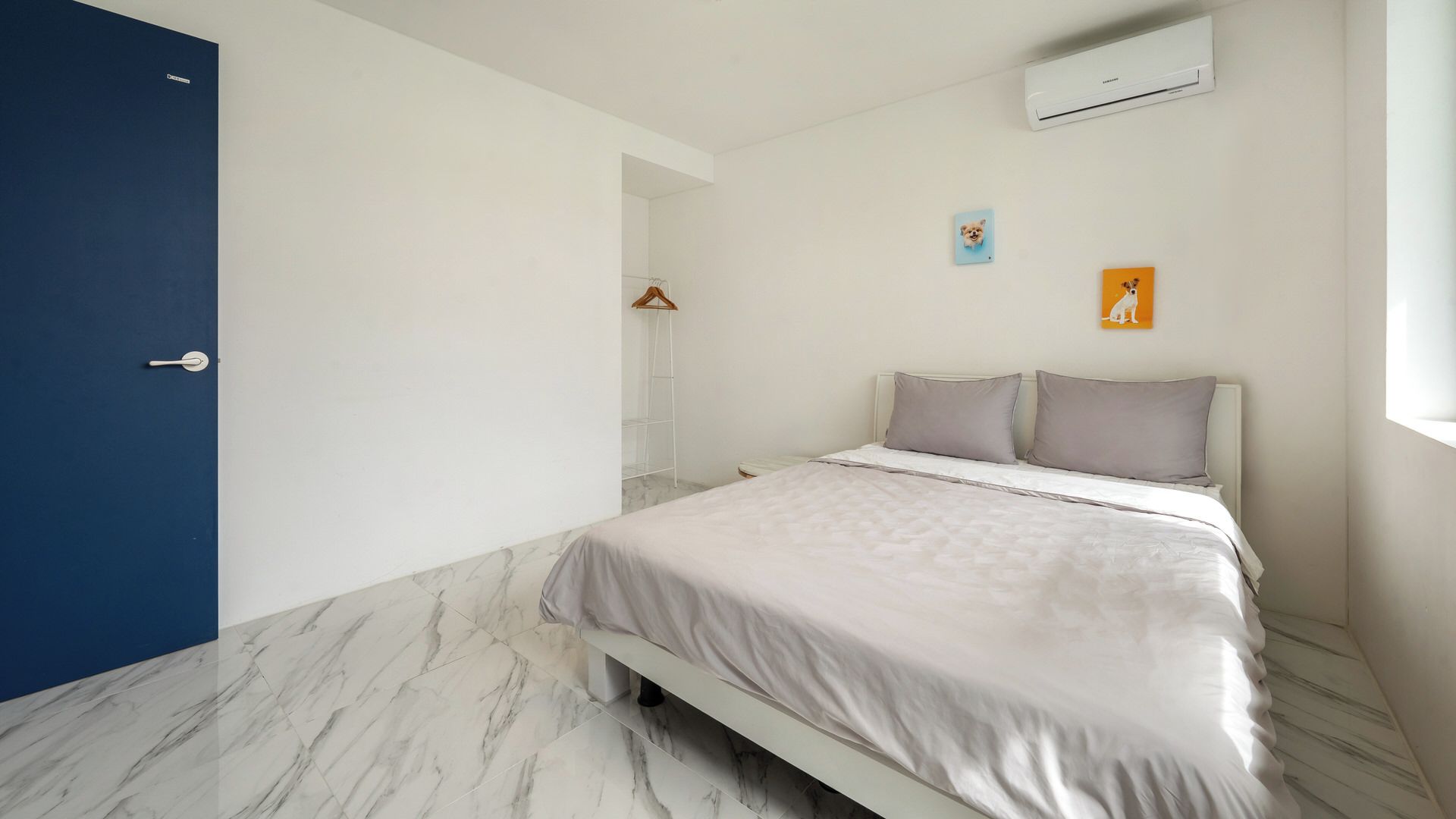Une chambre à coucher comprenant un lit, une armoire, un porte-manteau et un climatiseur fixé au mur.