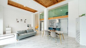 A modern living room with a grey sofa, a dining table with chairs, and a kitchen area with a refrigerator and stove. - Gyeongju Purspet Dog Pension (Gyeongju)