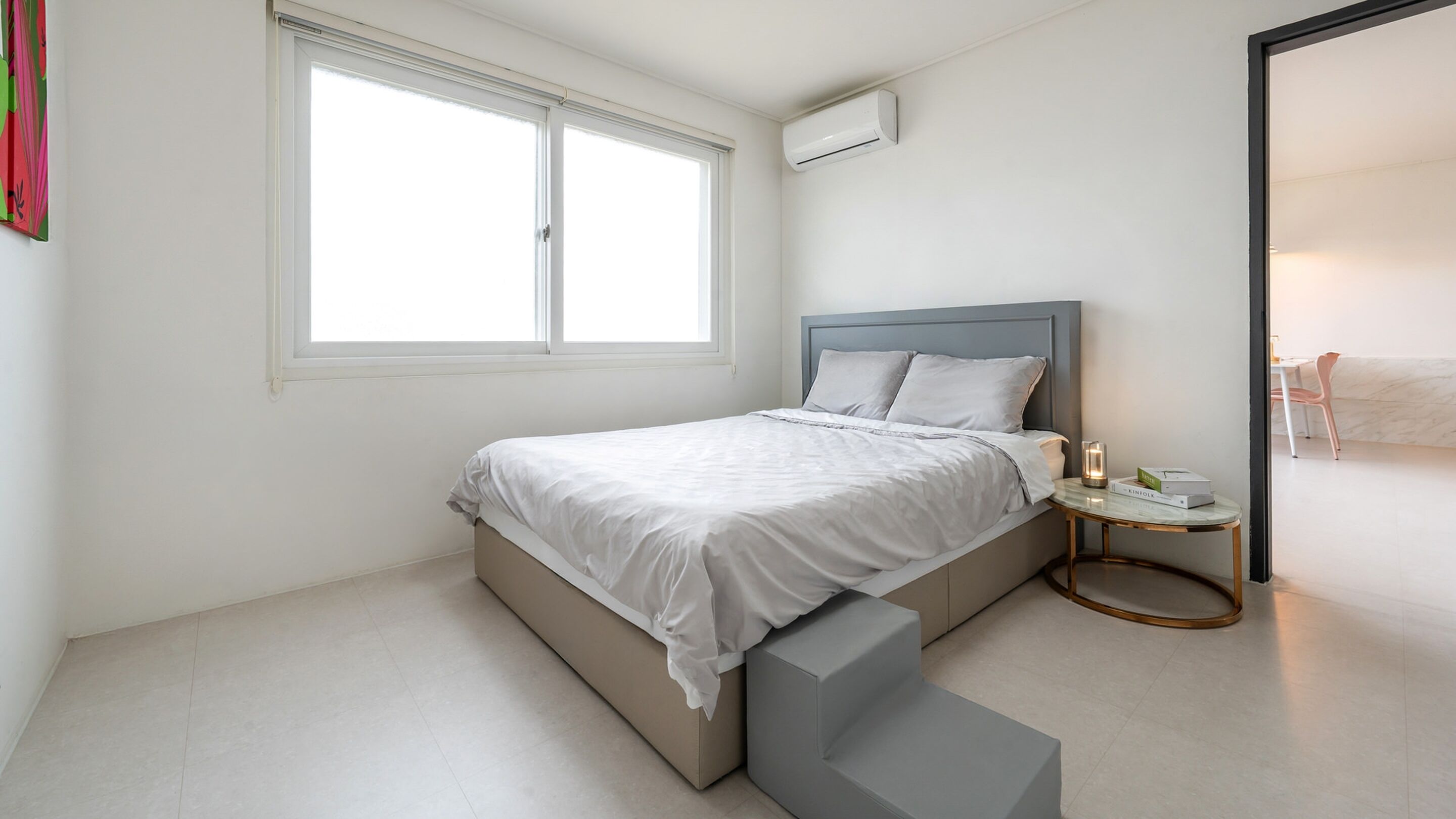 A modern bedroom with a bed, bedside table, and a window.