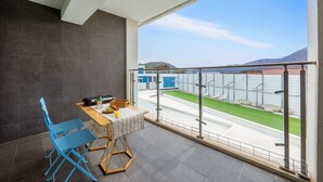 A balcony with a view of a sports field, a table with chairs, and a small seating area. - Gyeongju Purspet Dog Pension (Gyeongju)