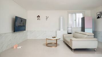 Una sala de estar moderna con un sofá blanco, una mesa redonda y un cuadro en la pared.