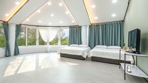 A modern, well-lit bedroom with two beds, a TV, and a view of greenery outside. - Hongcheon White Hill Pension (Hongcheon)