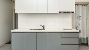 A modern kitchen with a white countertop, grey cabinets, and a stainless steel sink. - Hongcheon White Hill Pension (Hongcheon)