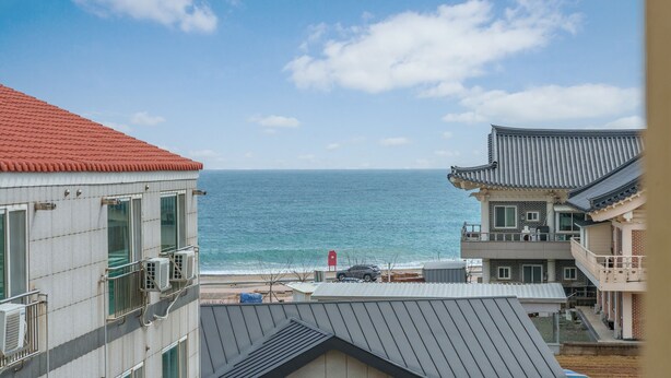 A coastal building with a red roof, a balcony, and a view of the sea.
