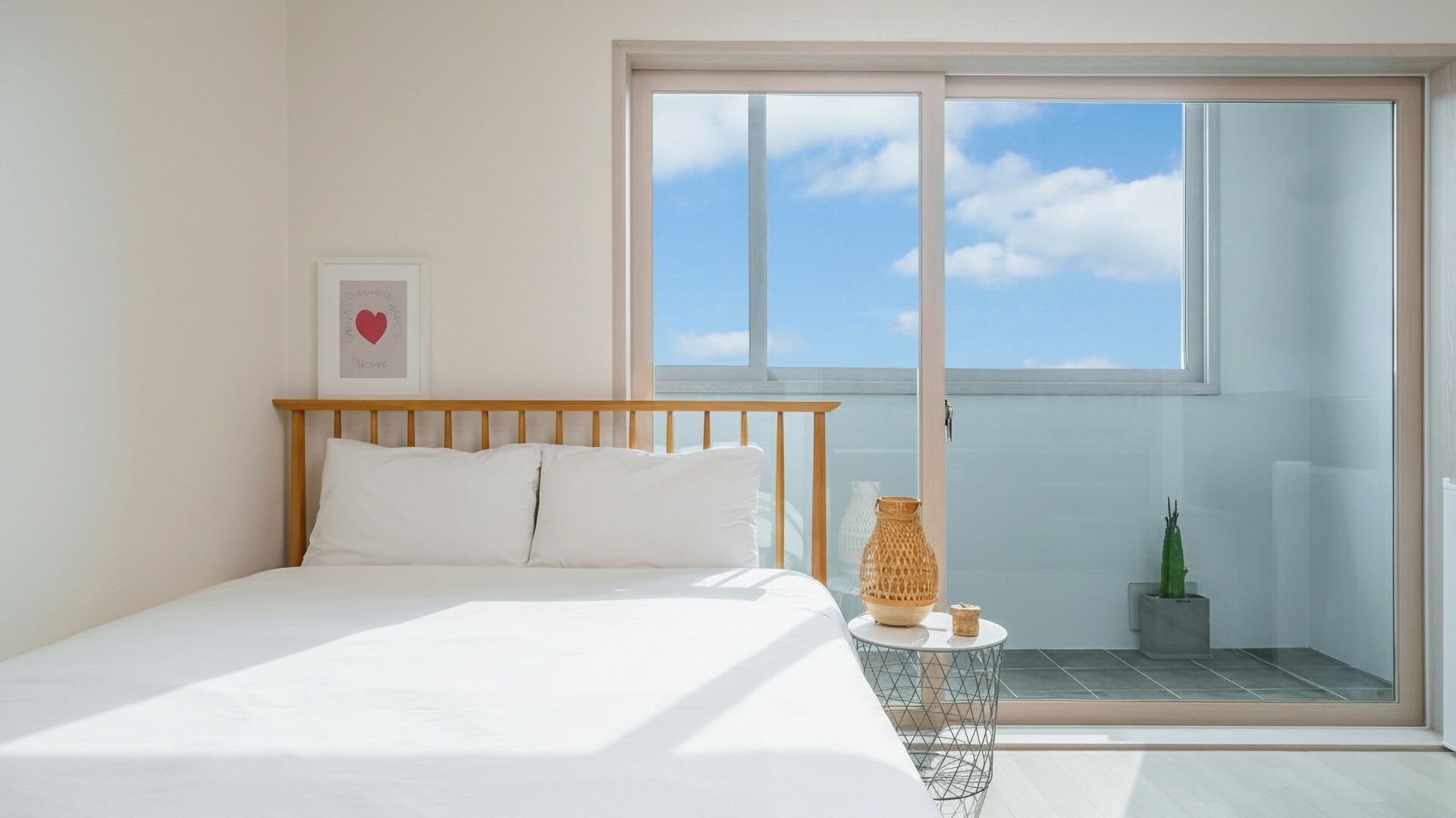 A bedroom with a bed, a small table, and a potted plant.
