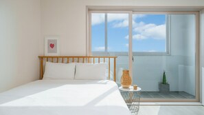 Un dormitorio con cama, una mesita y una planta en maceta.