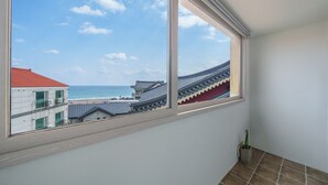 A room with a large window overlooking a beach and traditional buildings.