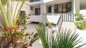 Un edificio residencial de varios niveles con balcones, plantas en macetas y una escalera.