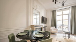 Ein Esszimmer mit rundem Tisch für sechs Personen, einem Kamin, einem Fernseher und einem Balkon mit Geländer.