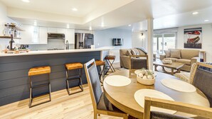 A modern kitchen with a central island, bar stools, and a dining area with a round table and chairs. - Clarklake Lakefront Apt w/ Hot Tub & Beach (Clarklake)