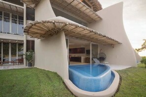 A modern house with a swimming pool, a covered patio, and a large window overlooking the pool.