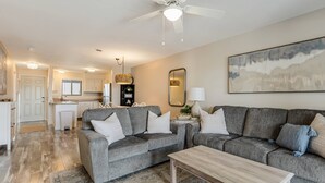 A modern living room with a grey sofa set, a wooden coffee table, and a large painting on the wall. - Newly Listed Ocean View and Dog Friendly Condo on Oak Island (Oak Island)