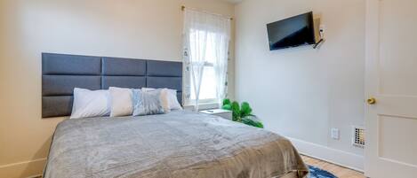 Une chambre à coucher avec un lit, un téléviseur fixé au mur et une porte.