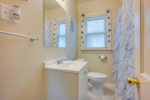 Un bagno con lavandino, WC e tenda da doccia con motivo marmorizzato.