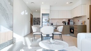 A modern kitchen with white cabinets, a built-in oven, and a coffee machine. - Burj Royale Elegance Cityscape From Your Balcony (Dubai)