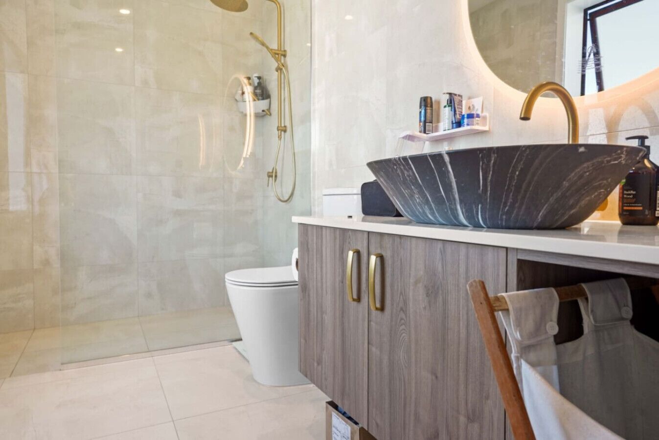 A modern bathroom with a large vessel sink, a glass-enclosed shower, and a toilet.