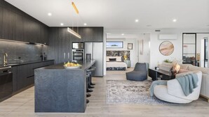 Una cocina moderna con armarios oscuros, una isla central y una zona de comedor con un sofá y una mesa de centro.