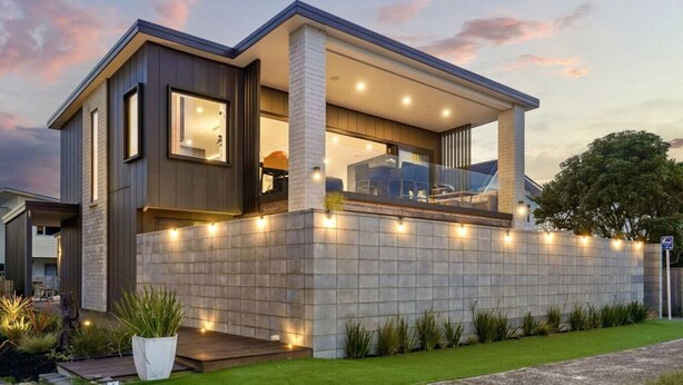 Una casa moderna de dos plantas con balcón, ventanas amplias y fachada de piedra.