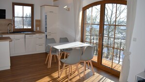 Eine moderne Küche mit Holzausstattung, einem Esstisch mit Stühlen und einem großen Fenster mit Blick auf verschneite Bäume.