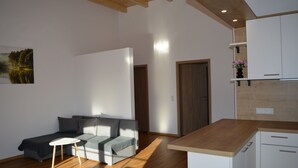 Ein modernes Wohnzimmer mit einer Couch, einem kleinen Tisch und einer Küchenzeile mit Holzarbeitsplatten und -schränken.