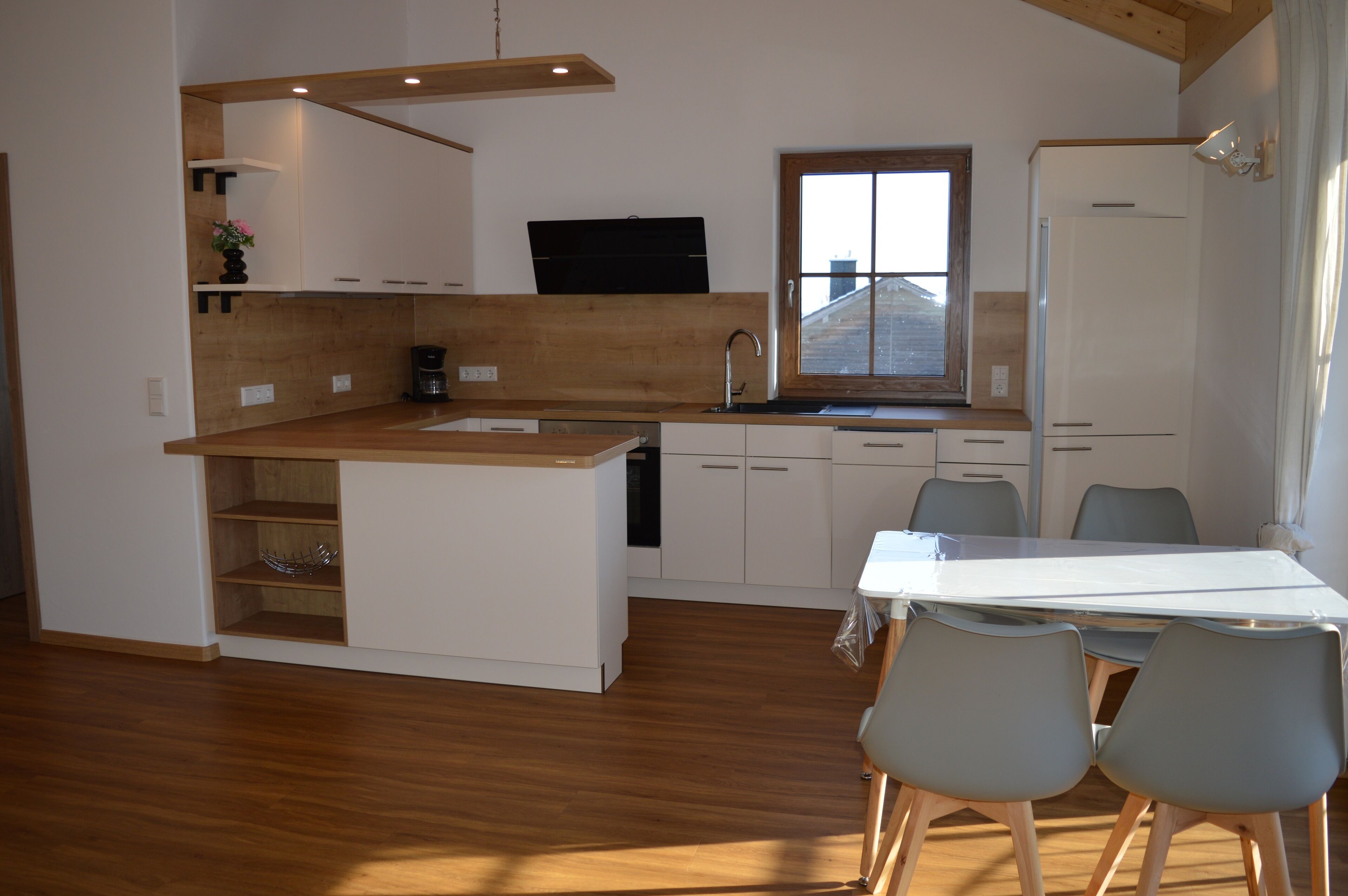 A modern kitchen with wooden countertops, a built-in sink, and a dining area with a table and chairs.