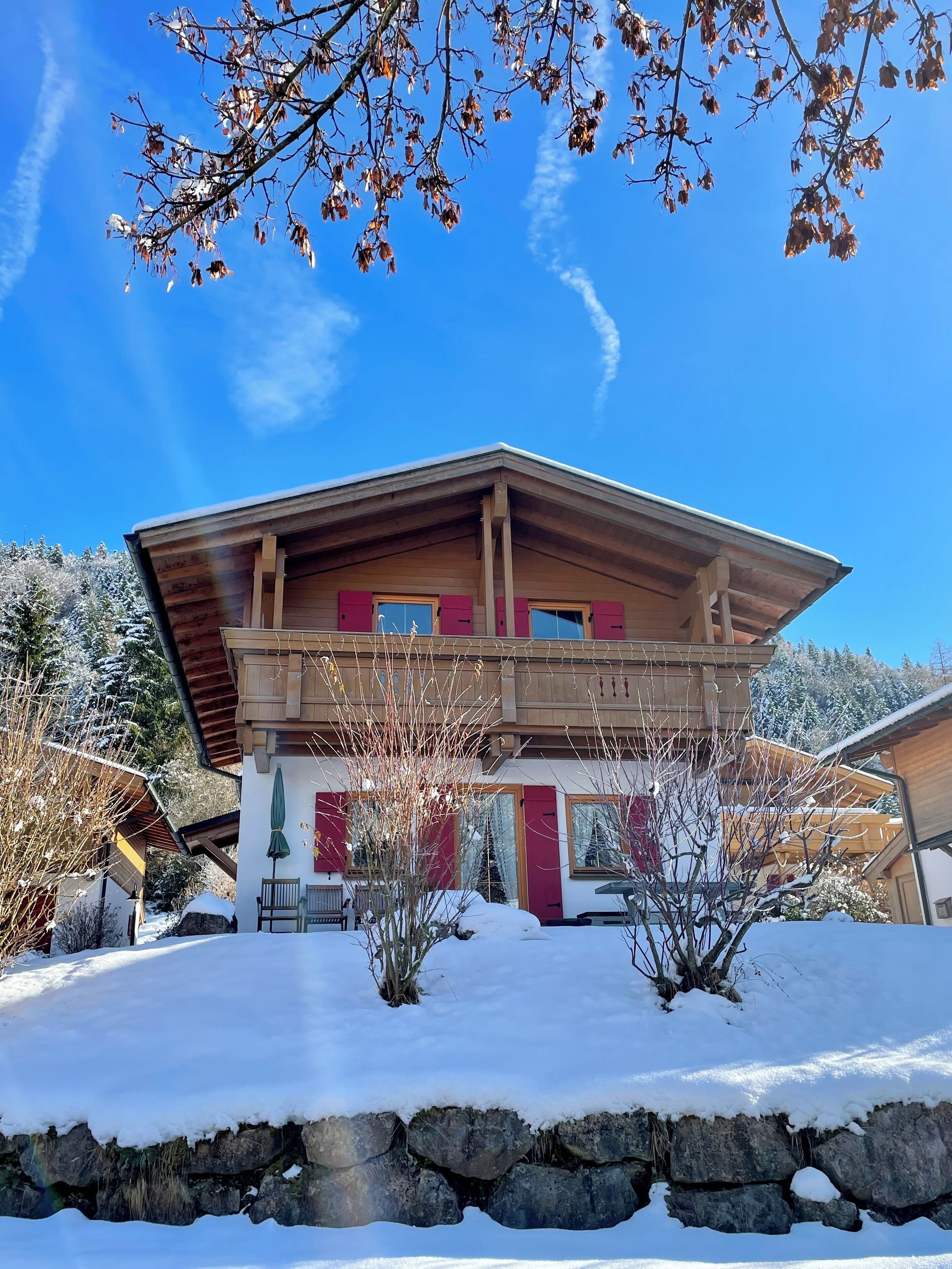Un chalet de dos pisos con fachada de madera, un balcón y cimientos de piedra.