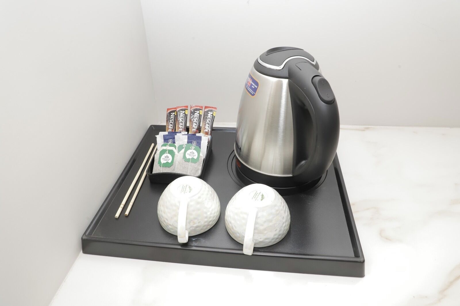 A tray with a coffee maker, tea packets, and two golf balls.
