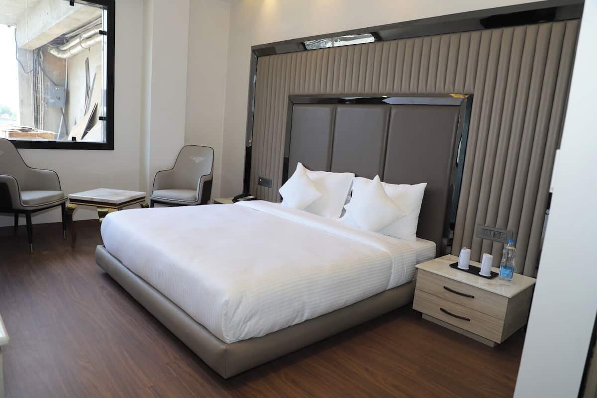 Une chambre d’hôtel moderne équipée d’un grand lit, d’un bureau, d’une chaise et d’une fenêtre avec des rideaux.