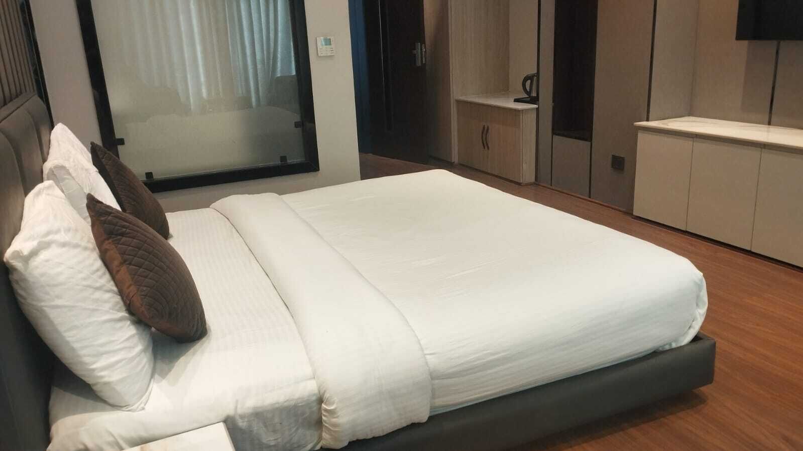 Una habitació d'hotel moderna amb un llit gran, una tauleta de nit i un armari.
