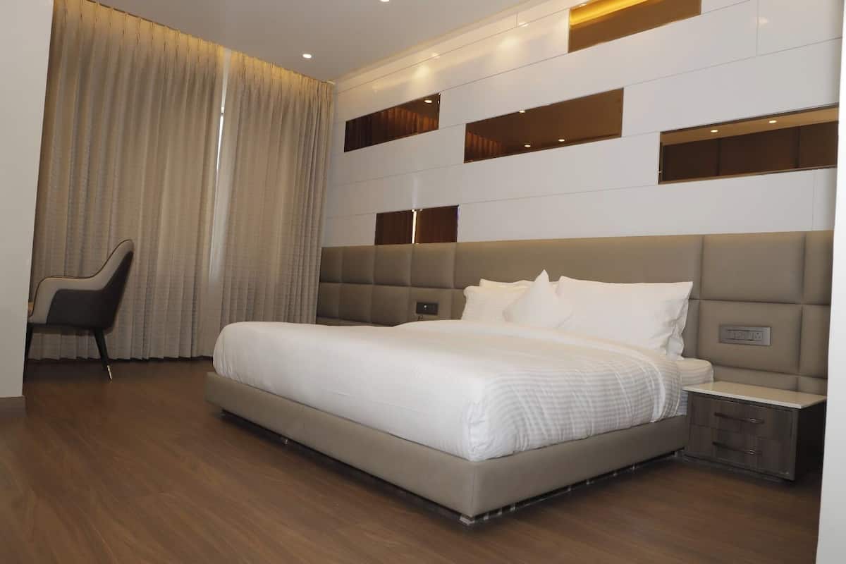 Une chambre d’hôtel moderne avec un grand lit, une table de chevet, une chaise et une horloge fixée au mur.