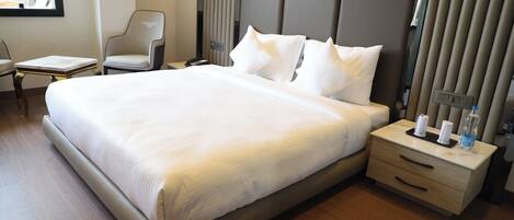 Une chambre d’hôtel avec un grand lit, une table de chevet avec une lampe, une chaise et une fenêtre.