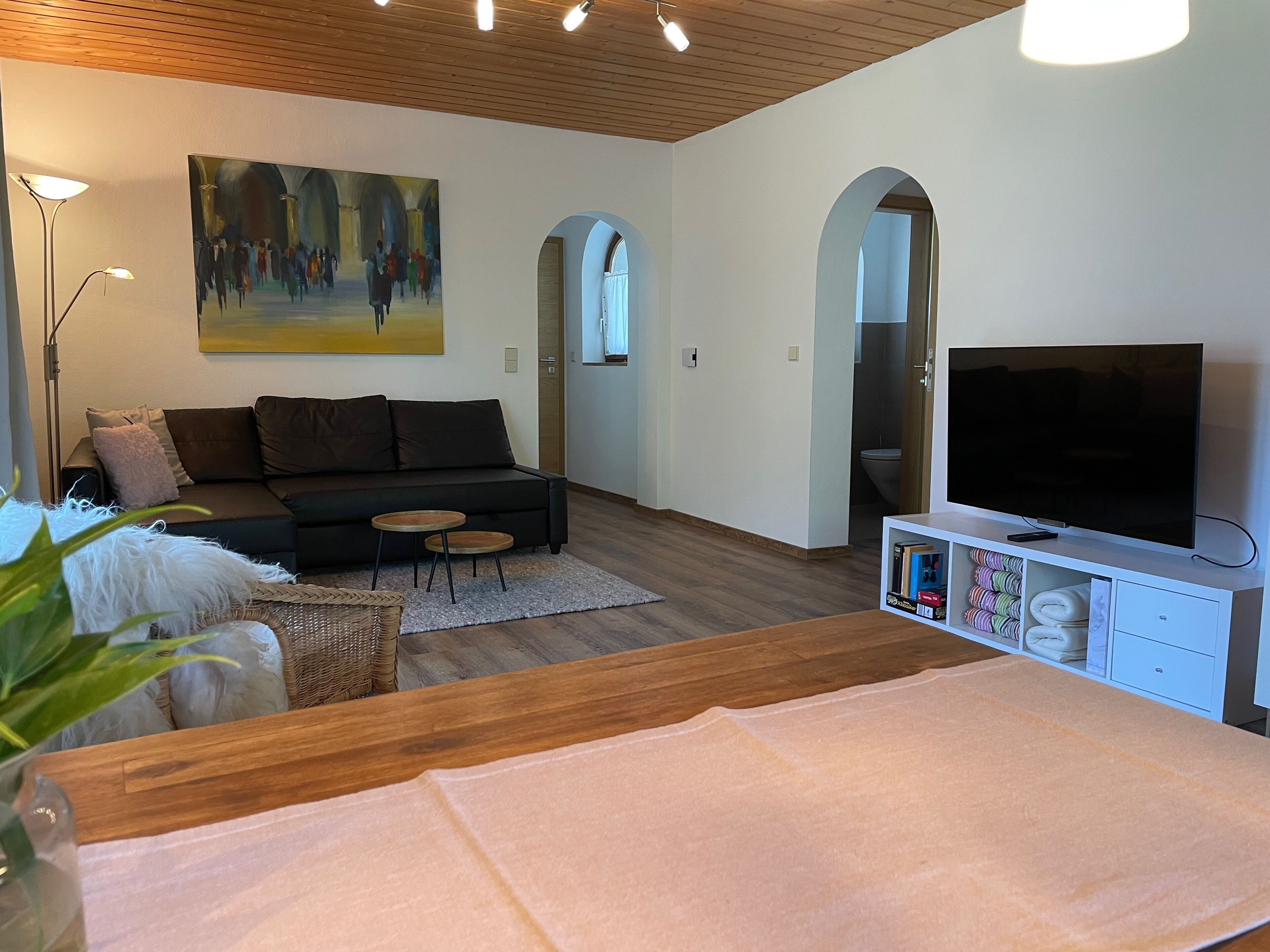 A modern living room with a sofa, TV, and a painting on the wall.