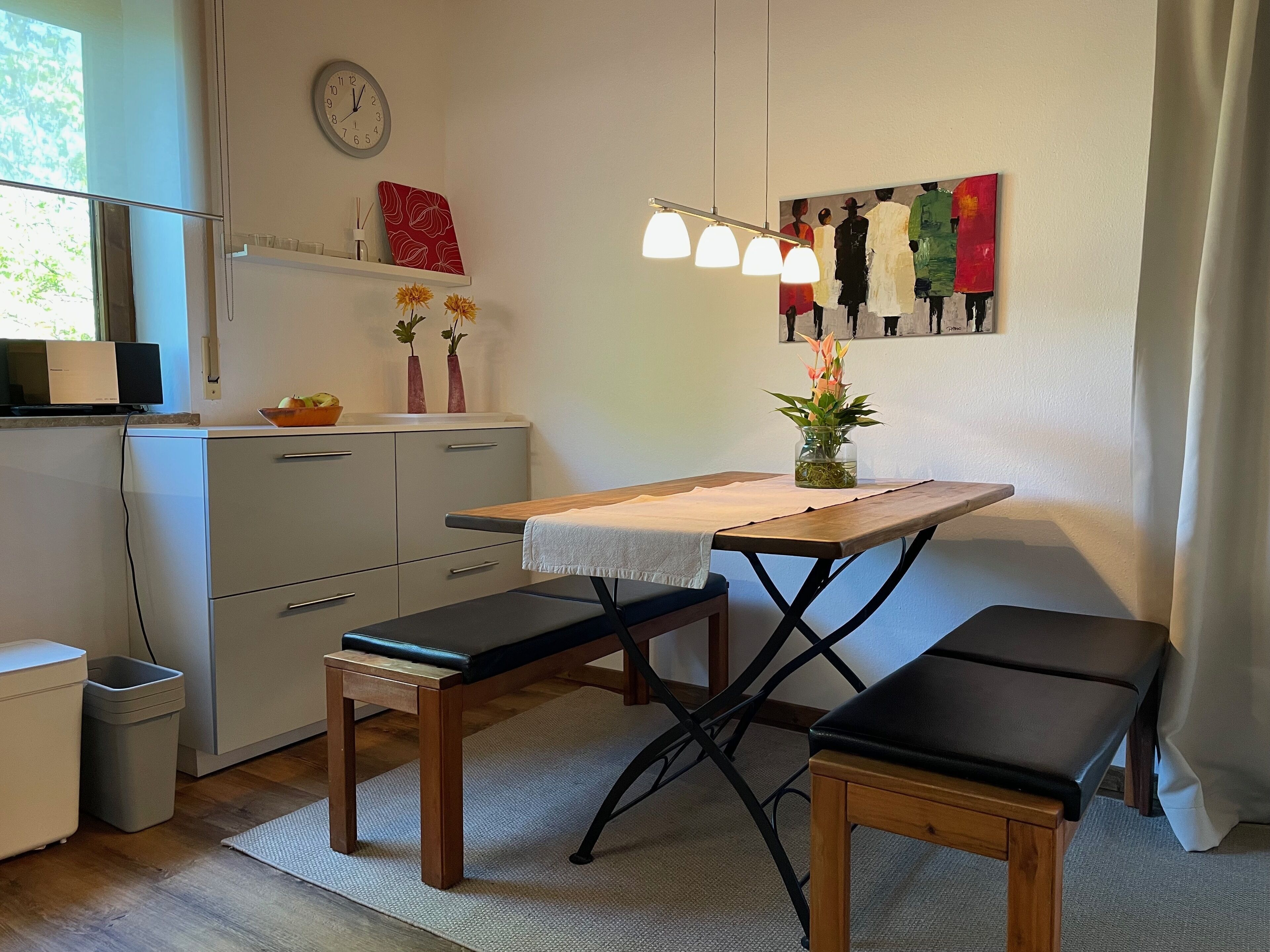 A compact kitchen with a wooden table, bench, and a clock on the wall.