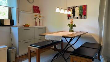 A compact kitchen with a wooden table, bench, and a clock on the wall.