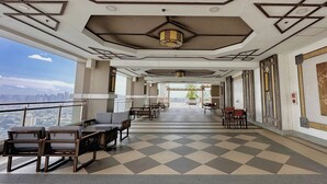 A spacious indoor area with a checkered floor, seating arrangements, and a view of a cityscape through large windows. - 2BR Gem in MNL w/Pool, Fast WiFi, Netflix Near Luneta US Embassy & Intramuros (Manila)