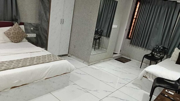 Una habitación de hotel con una cama, una mesita, una silla, un espejo y un armario.