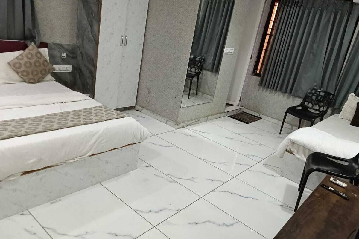 Una habitación de hotel con una cama, una mesita, una silla, un espejo y un armario.