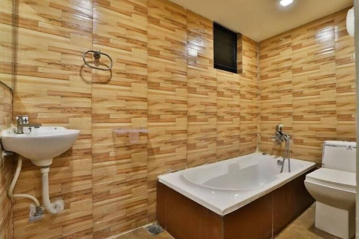 Un baño con diseño de pared de madera, un lavamanos, una bañera y un inodoro.
