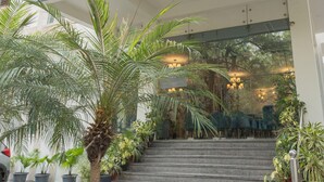 Exterior de Ahuja Residency, con un letrero sobre la entrada, una escalera que lleva a la puerta y plantas en macetas alrededor.