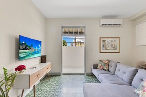 Un salon moderne doté d’un téléviseur à écran plat, d’un canapé, d’une table basse et offrant une vue à travers une porte vitrée.