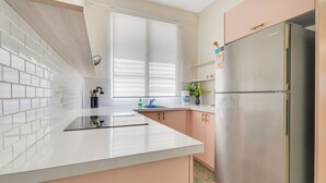 A modern kitchen with white and pink cabinetry, a stainless steel refrigerator, and a window providing natural light. - Apartment in Miramar for 6 People with a Power Generator (San Juan)