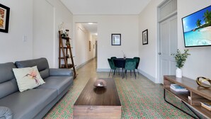 A living room with a grey sofa, a wooden coffee table, and a dining area with a table and chairs. - Apartment in Miramar for 6 People with a Power Generator (San Juan)