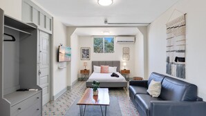 Un dormitorio con cama, mesitas de noche, cómoda, sofá, mesa de centro y ventana con vistas.