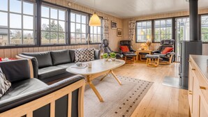 Een gezellige woonkamer met een bank, stoelen, een tafel en een open haard.