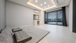 A modern bedroom with a large bed, a desk, and a view of a snowy landscape through the window. - Gangneung Taurus Pension (Gangneung)