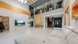 A modern living room with a large flat-screen TV, a sofa, and a Christmas tree. - Gangneung Taurus Pension (Gangneung)
