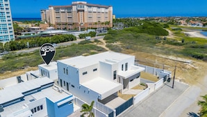 A modern building with a flat roof and a large parking area. - Palmbeach 623: 5 min walk to beach  by Bocobay (Noord)